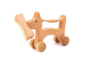 Photo of a wooden dog with bone on wheels  of beech. Toy made of wood  on a white isolated background.A toy for entertaining children and resting parents