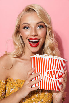 Image of glamour young woman with red lipstick smiling and holding popcorn bucket