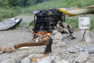 Obraz premium Axe in stump. Axe ready for cutting timber. Woodworking tool. Lumberjack axe in wood, chopping timber. Travel, adventure, camping gear