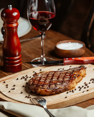 neat steak on a wooden stand with a glass of red wine