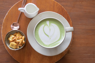 Coffee cup with Green Matcha latte art foam on wood table in coffee shop with copy space.Coffee is one of the most popular beverages.Improve Energy Levels and Burn Fat
