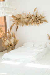 Minimalist interior bedroom. Flower and reeds installation in Scandinavian styled interior