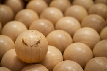Wooden ball with pattern like brown eyebrow on face for insert emotion put around pattern less woodballs background. Photo for Leadership or Different thinking or Team work concept. Selective focus.