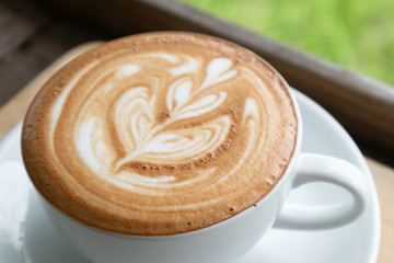 Coffee cup latte art in heart shape with a cup of dark coffee and dark chocolate on wooden table.Frothy drink for coffee break after working or weekend meeting