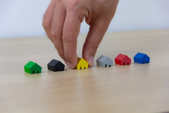 Hand select home, concept different colored game pieces