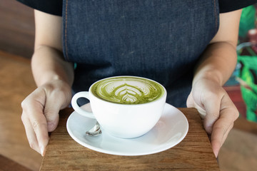 Coffee cup with Green Matcha latte art foam on wood table in coffee shop with copy space.Coffee is one of the most popular beverages.Improve Energy Levels and Burn Fat