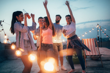 Happy friends with drinks toasting at rooftop party at night