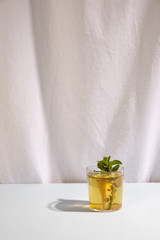 Fresh delicious drink with mint leaf against white curtain