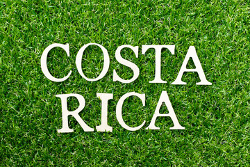 Wood alphabet letter in word costa ricaon green grass background