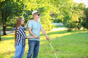Blind mature man with daughter walking in park
