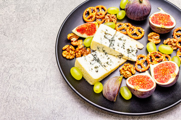 Cheese plate with blue cheese, walnuts, figs, grapes, pretzels