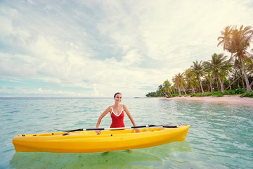 Young woman holding the sea kayak in the tropical calm lagoon.