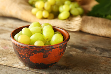 Bowl with sweet grapes on wooden table
