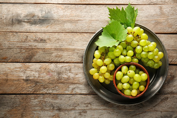 Plate with sweet grapes on wooden background