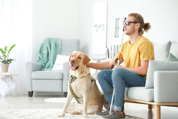 Blind young man with guide dog at home