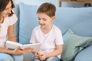 Little boy and his elder sister reading book at home