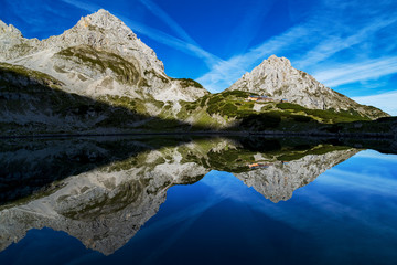 Obraz premium Morning sunrise at lake Drachensee in the alps, austria near Reutte, ehrwald. View of the Coburger Hütte and mountain vorderer Drachenkopf