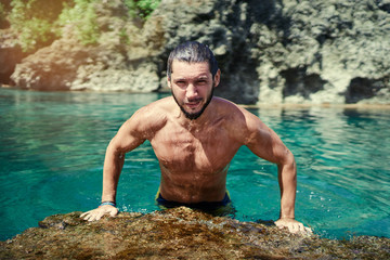 Summer vacation. Young bearded man bathing at sea natural pool.