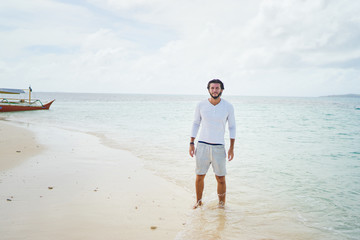 Tropical vacation. Portrait of young handsome man on the white sand beach.