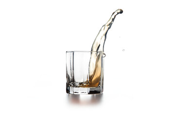Whiskey splash in glass with ice on light background..