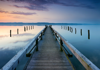 Long Wooden Pier into Calm Lake at Sunrise	