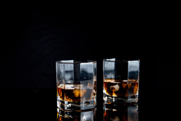 Two glasses of whiskey with ice isolated on black background..