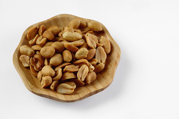 wood plate of salted peanuts isolated on white background. snack to beer