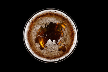 World map shape on foam in glass of beer on black background Top view