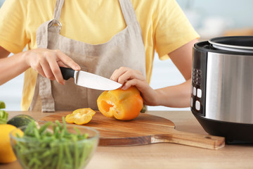 Woman cutting vegetables for stewing in multi cooker