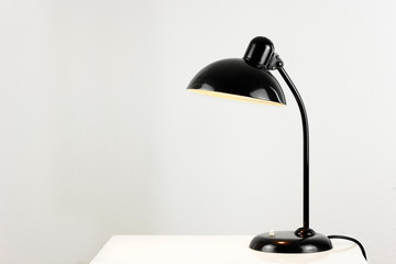an antique black table lamp from the 20s bauhaus era standing on an old desk commode isolated on...
