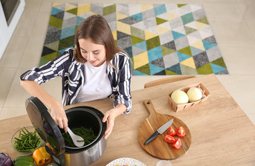 Woman using modern multi cooker in kitchen