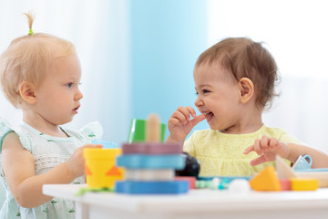 Kids playing educational toys in playroom at nursery - obrazy, fototapety, plakaty
