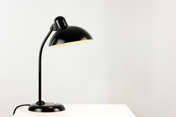 an antique black table lamp from the 20s bauhaus era standing on an old desk commode isolated on white background very rare in original condition design icon close up living room minimalistic design - obrazy, fototapety, plakaty