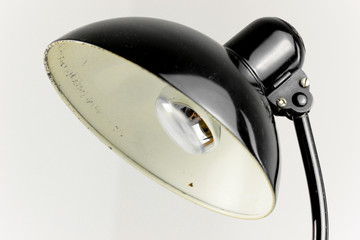 an antique black table lamp from the 20s bauhaus era standing on an old desk commode isolated on...