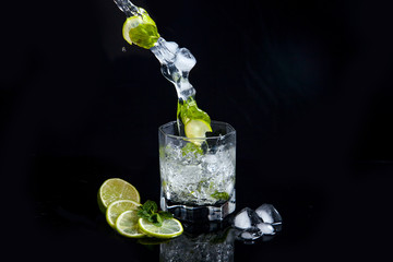 Summer cocktail mojito with splash on black background..
