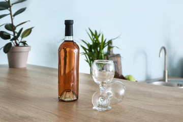 Bottle of alcoholic drink and empty glasses on kitchen table