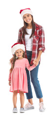 Fototapeta premium Woman and her little daughter in Santa hats on white background