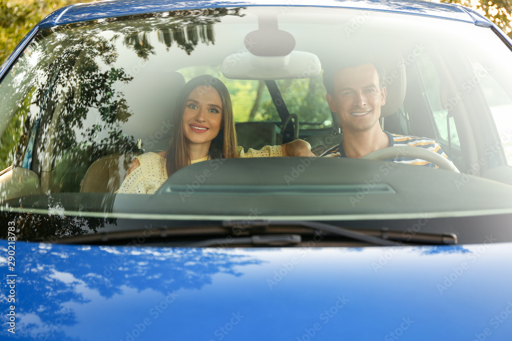 Wall mural happy couple sitting in their new car, view from windshield window