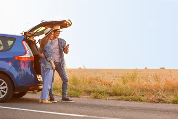 Happy couple using mobile phone for navigation in countryside