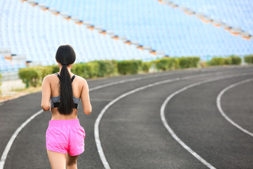 Sporty Asian woman running at the stadium