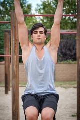 Obraz premium a sporty boy raising his legs hanging from a bar, working his abs, fully frontal