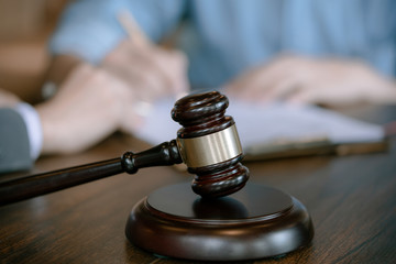 Judge gavel on wooden teable background with  businessman and female lawyers having a meeting at a law firm. Concepts of law.