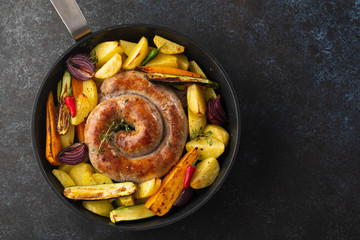 Sausages with potatoes, zucchini, carrots and thyme in a grill pan. Top view.