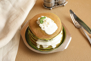 Plate with green pancakes on table