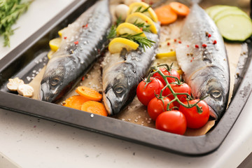 Tray with raw mackerel fish and vegetables on table