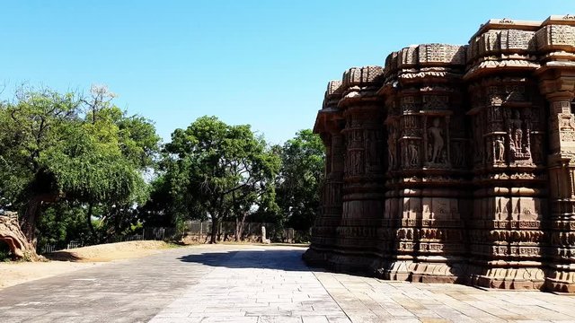 a dove flies of from intricately carved exterior and pillars of the backside of sun temple Modhera.