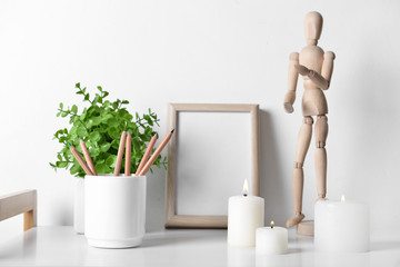 Beautiful burning candles with pencils and photo frame on table