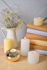 Fototapeta na wymiar Beautiful burning candles with books on table in room