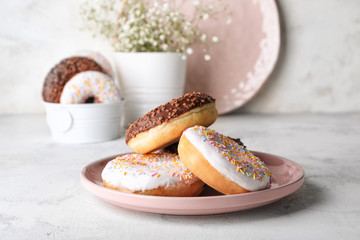 Plate with tasty donuts on light background