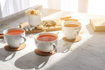 Cups of hot tea on white wooden table